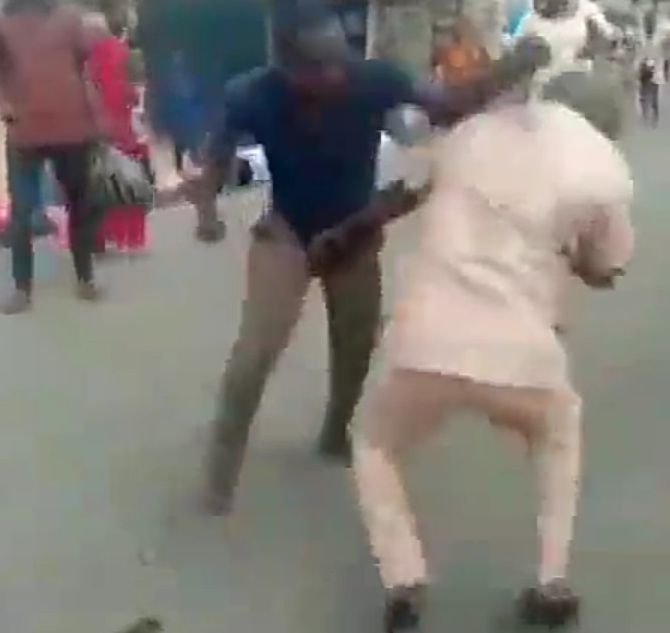 Two grown men fight over a woman in the middle of a street in Nigeria while spectators watch (video)